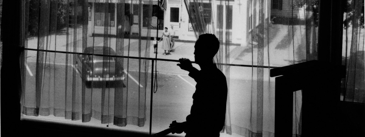 Norman Rockwell peering out studio window onto Main Street, Stockbridge