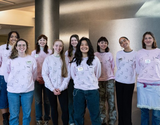 A group of smiling people all wearing the same sweatshirt