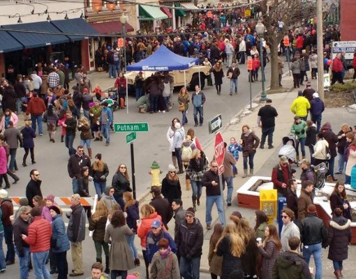 crowd of people walking around a city during an event