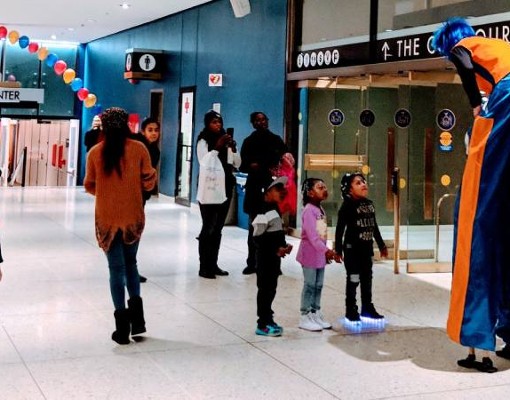person walking on stilts talks to kids at kidz expo