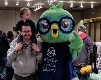 dad and toddler pose with albany public library bird mascot