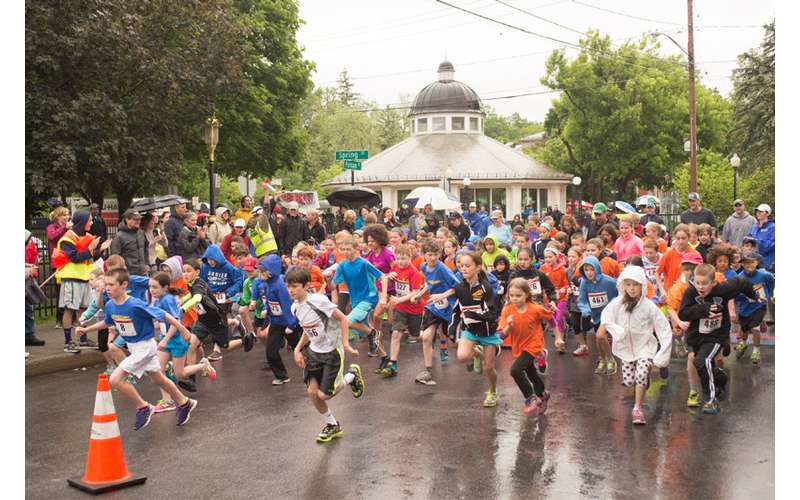 large group of kids running down a wet street