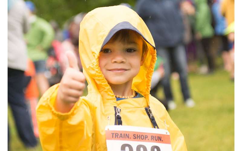 a boy in a yellow rain jacket giving a thumbs up