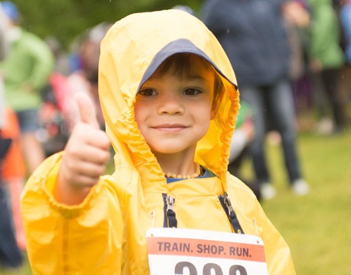 a boy in a yellow rain jacket giving a thumbs up
