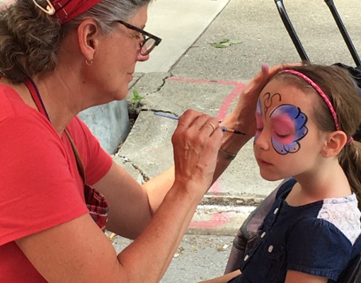 woman doing a face painting with a little girl
