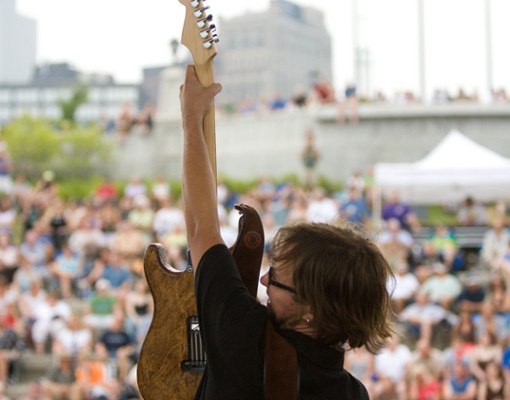 man on stage holding up guitar