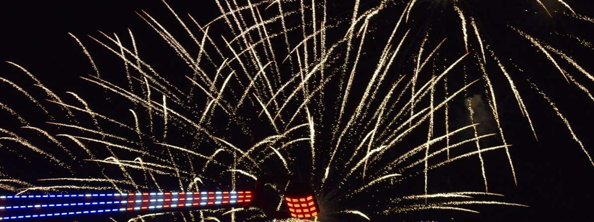 fireworks and part of an amusement park ride lit up in fourth of july colors
