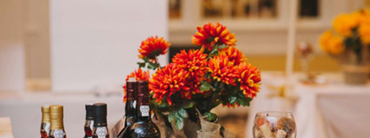 bottles of wine, glass of wine, chocolate, and flowers on a table