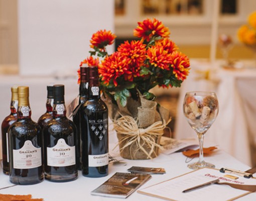 bottles of wine, glass of wine, chocolate, and flowers on a table