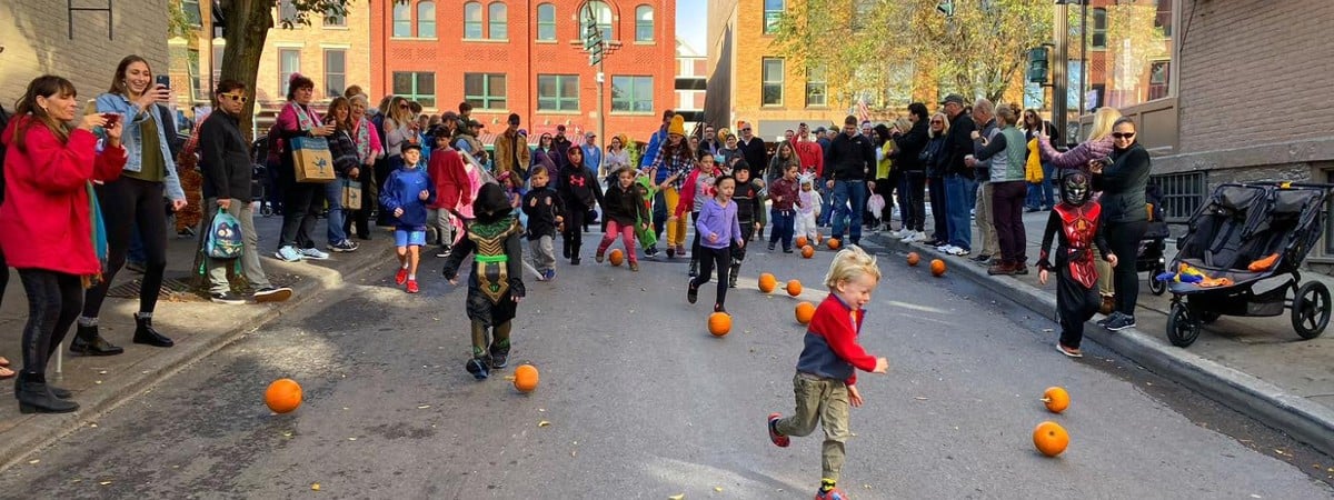 kids rolling pumpkins down a street