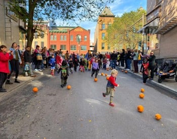 kids rolling pumpkins down a street
