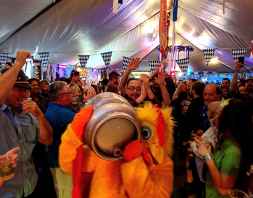 people at oktoberfest tent and person dressed as chicken