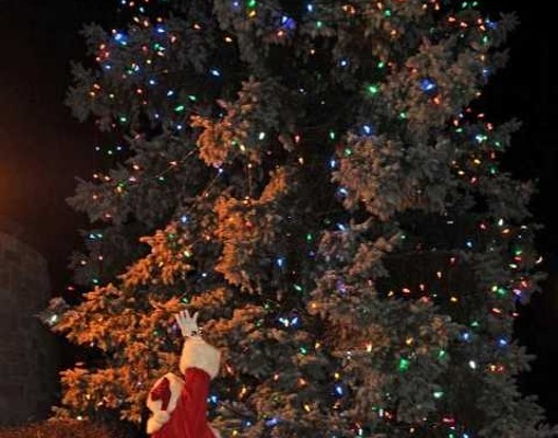Santa in front of a huge lit tree