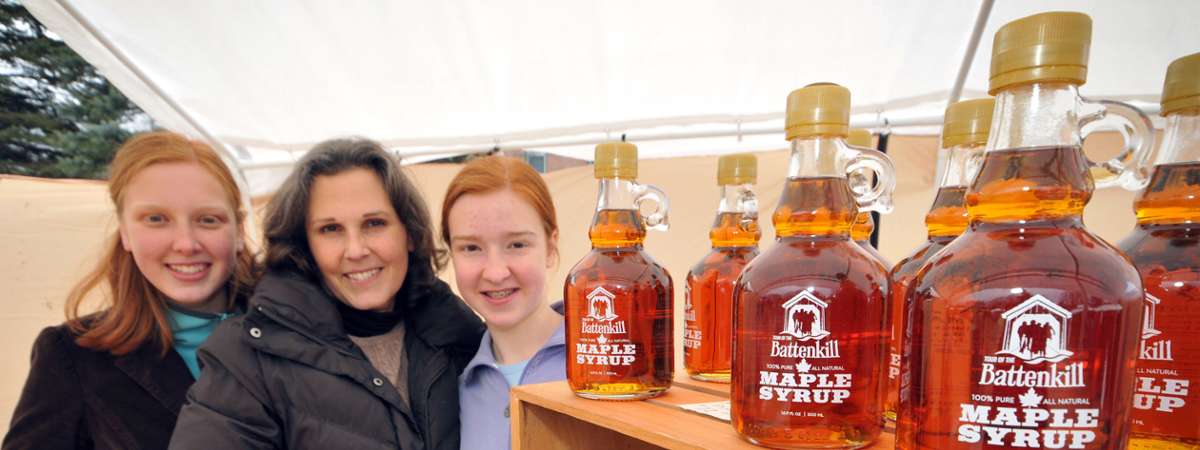 women posing next to maple syrup