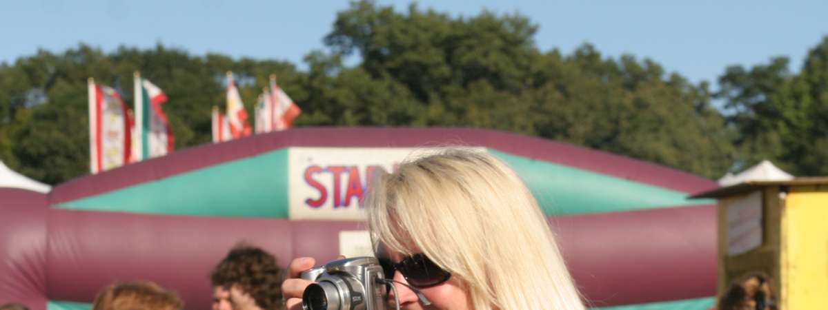a woman with a feather boar taking a picture with a camera