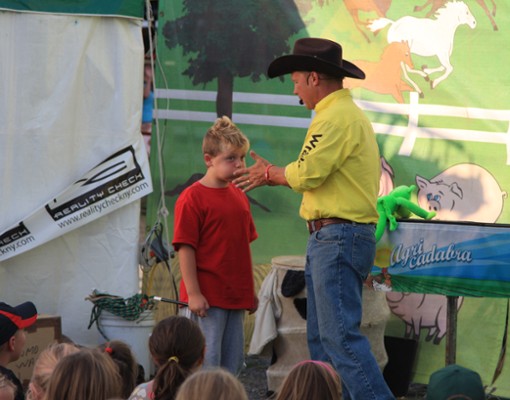 a man with a cowboy hat doing a demonstration with a little boy in a red shirt