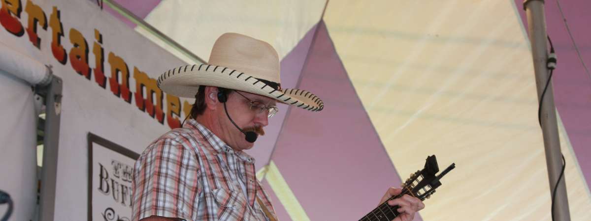 man with plaid shirt and cowboy hat performing