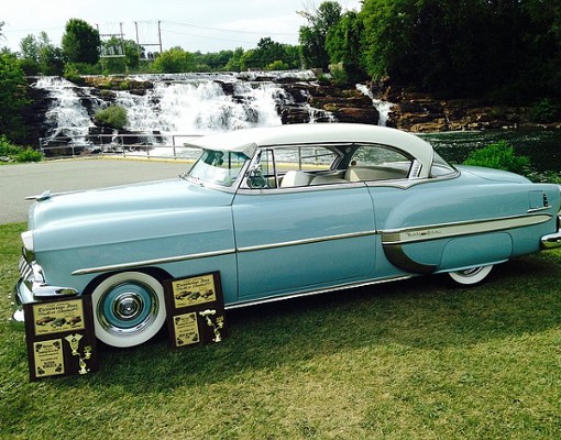 a blue classic car with an award plaque in front of it