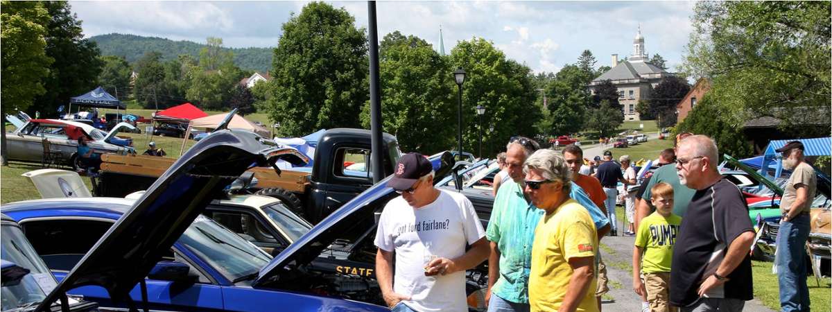 spectators looking up close at classic cars with the hoods up