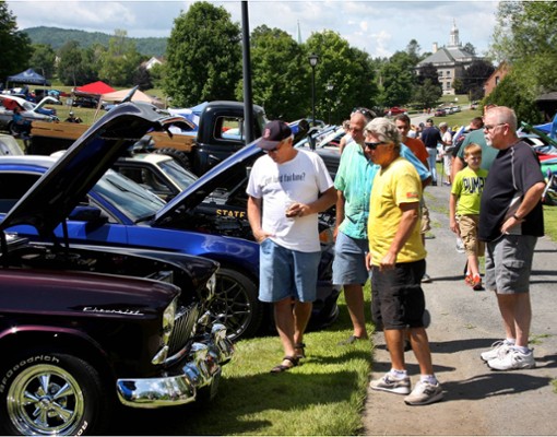 spectators looking up close at classic cars with the hoods up