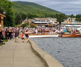 people walking along promenade by water and antique boat show