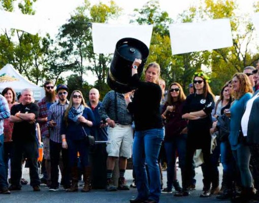 woman doing a keg toss with crowd around her