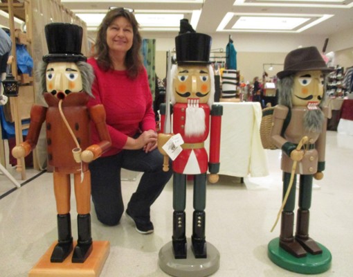 woman kneeling near wooden nutcracker dolls