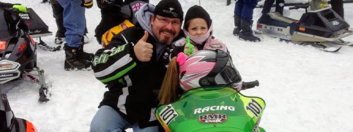 man and little girl with snowmobile