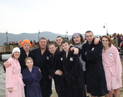 people in warm robes standing near a cold lake