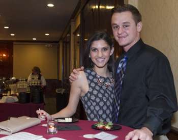 a couple posing behind a red table