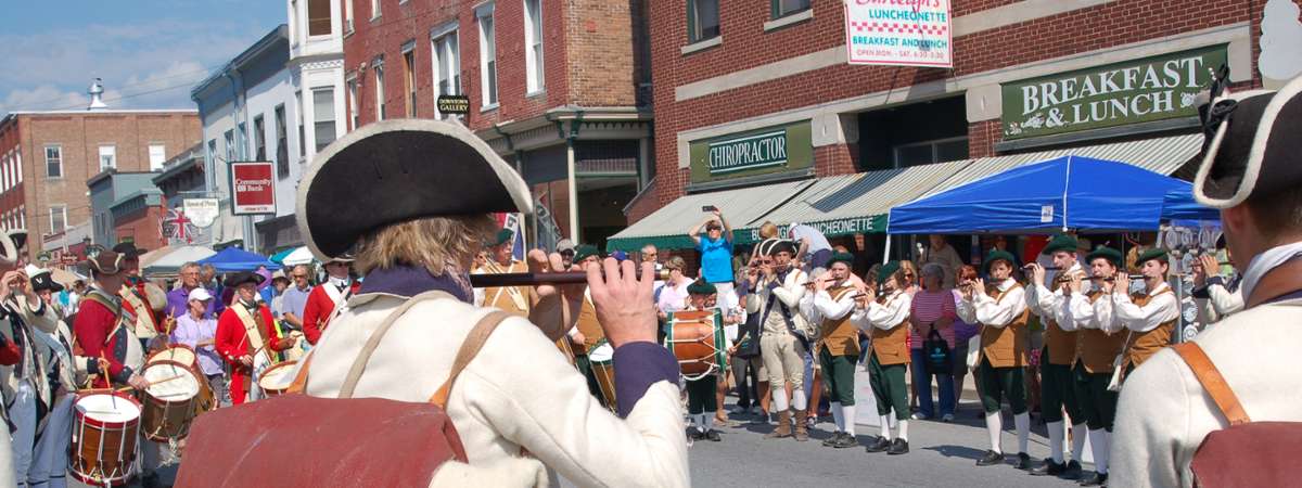 fife and drum players performing for a crowd on a street