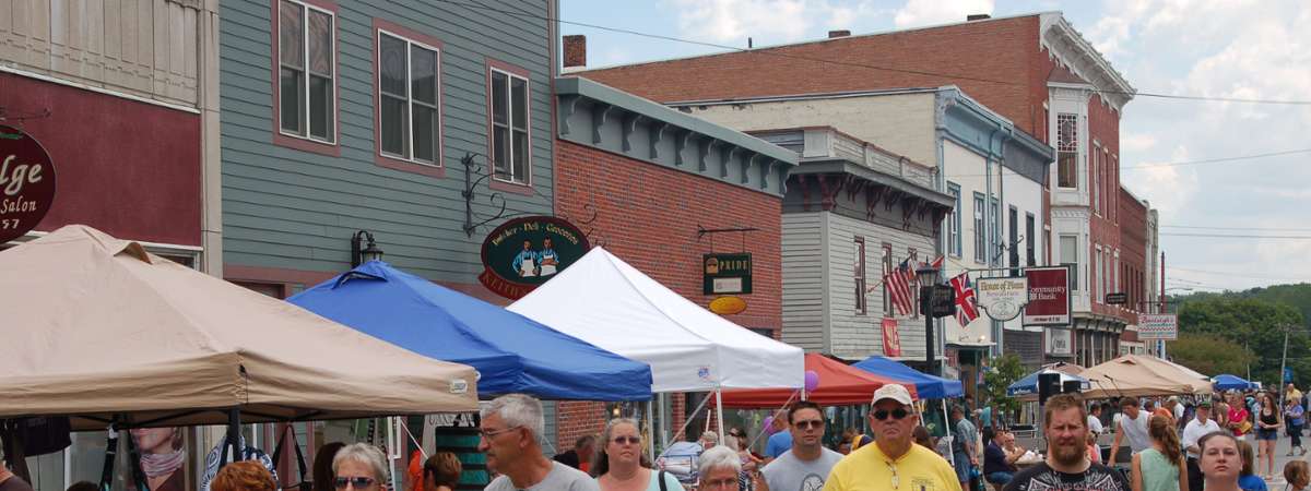 people walking down Montcalm Street by vendor tents for Ticonderoga's Streetfest