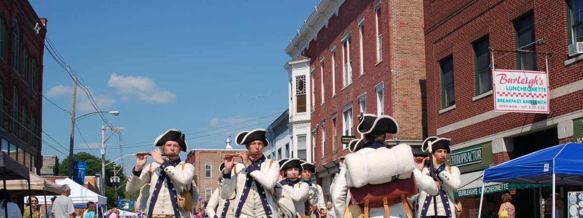 fife and drum corps standing on a street playing instruments