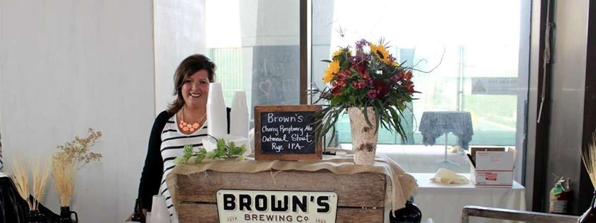 a woman standing behind a brewery table