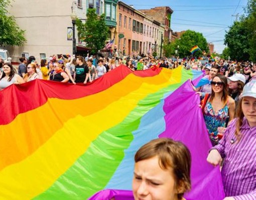 people holding pride flag in a parade