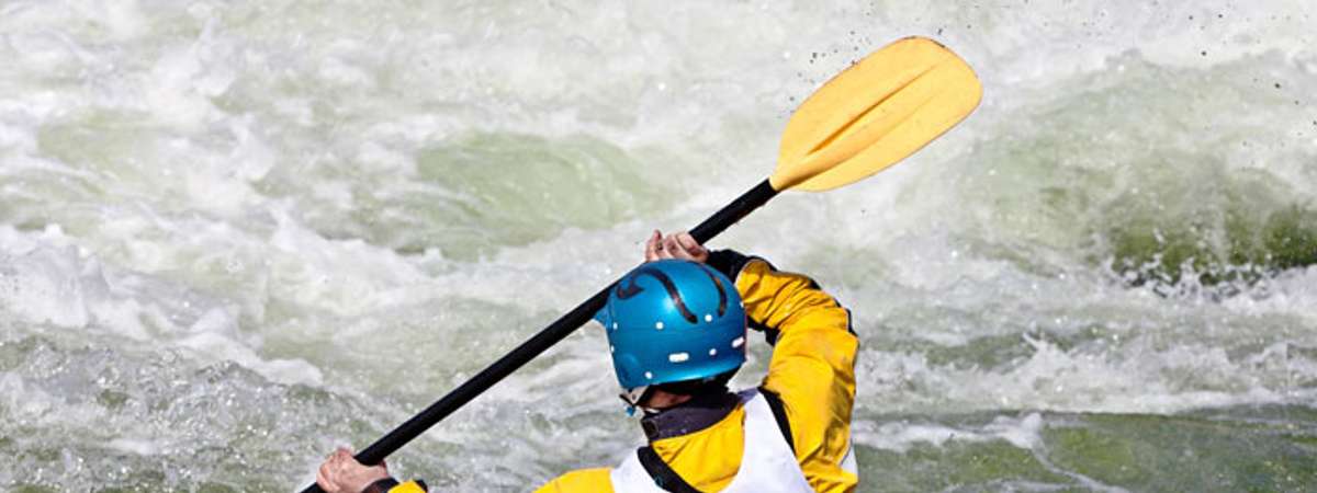 kayaker paddling through rapids