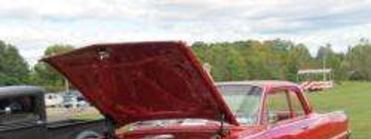 a red classic car with the hood up
