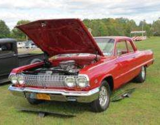 a red classic car with the hood up