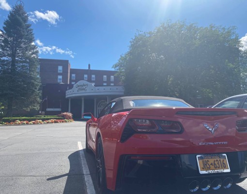 red corvette parked in front of queensbury hotel