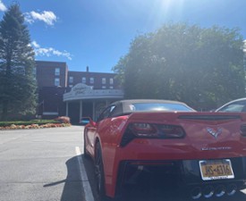 red corvette parked in front of queensbury hotel