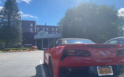 red corvette parked in front of queensbury hotel