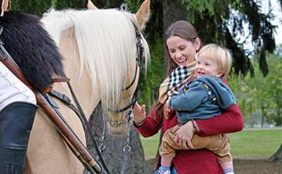 woman holding a child petting a horse