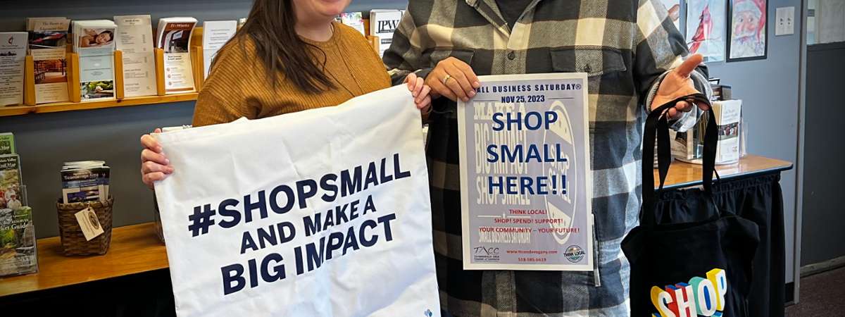 two people in store holding up small business saturday signs