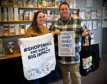 two people in store holding up small business saturday signs