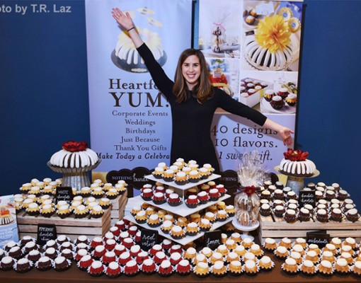 woman standing behind a display of cupcakes
