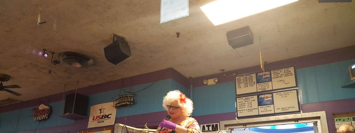 a woman speaking over a loudspeaker in a bowling alley