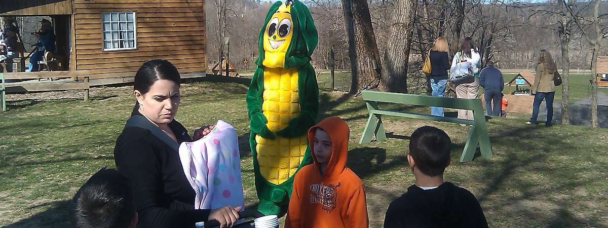 group of people outside with a person in a corn cob costume