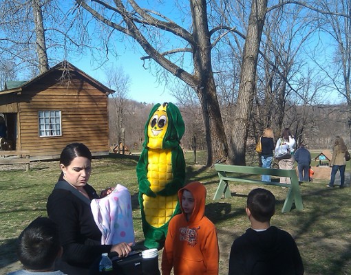 group of people outside with a person in a corn cob costume