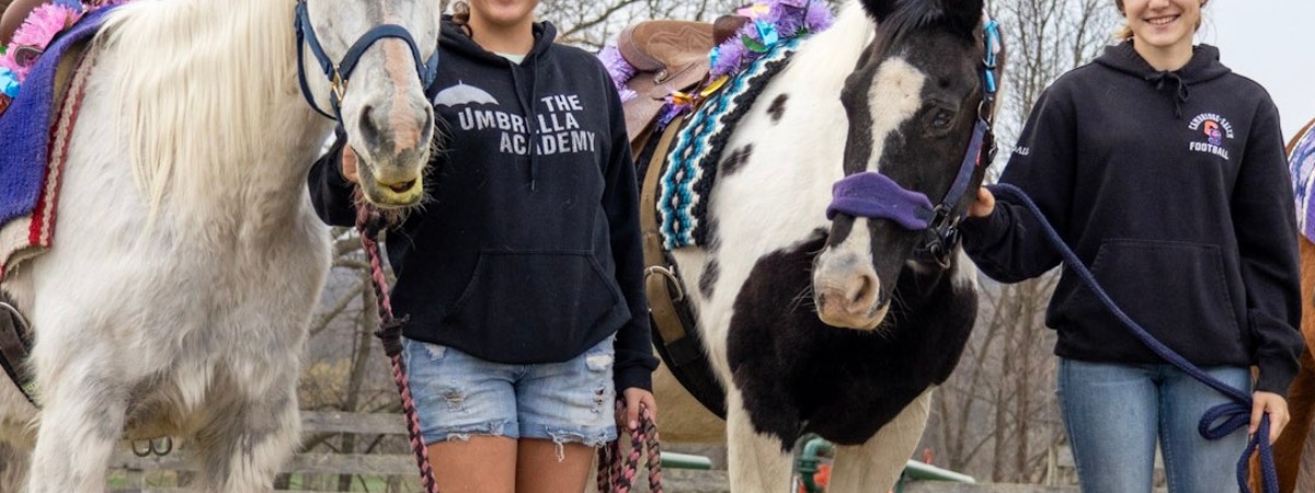 two girls standing with horses