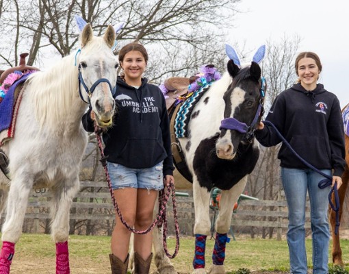 two girls standing with horses